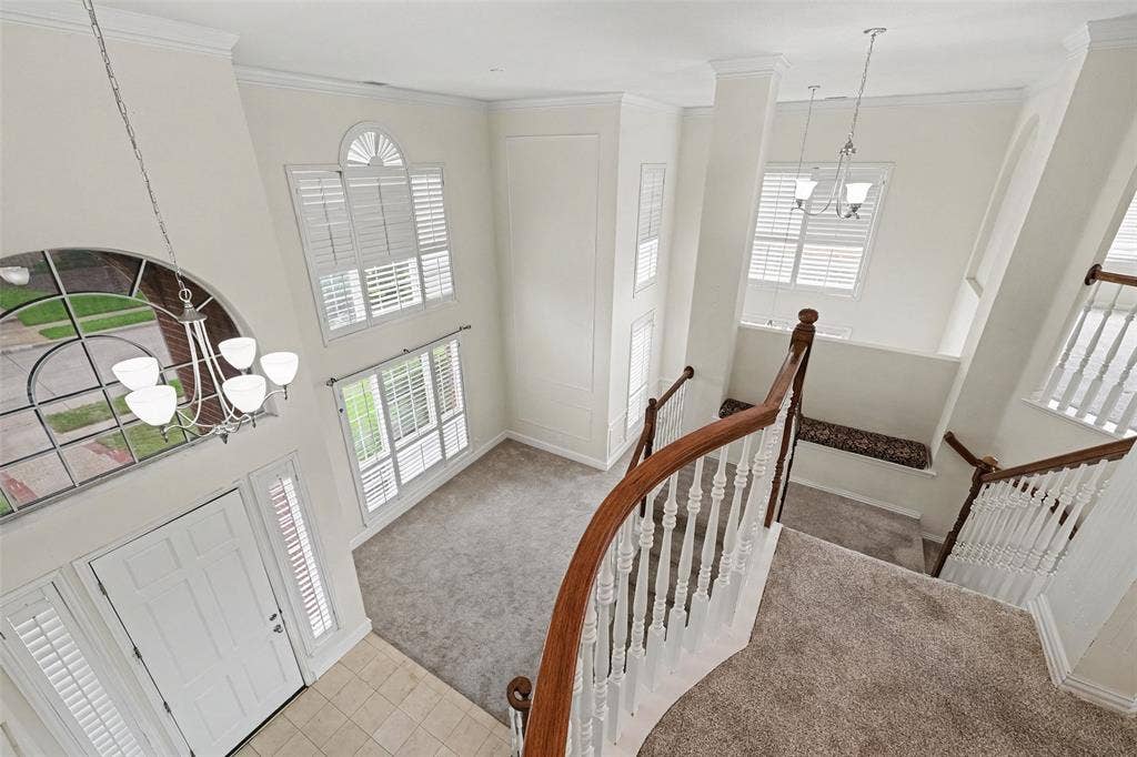 7813 San Isabel Drive, Plano, TX 75025 Two-story foyer with a curved wood-finish staircase, large arched window, and overhead chandelier