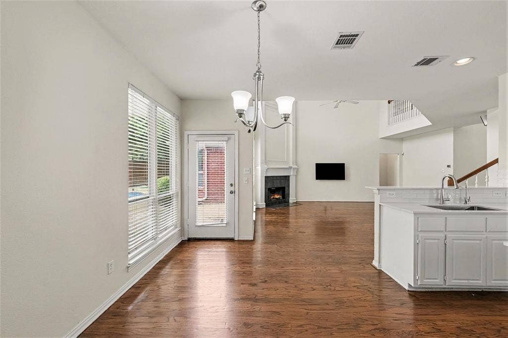 7813 San Isabel Drive, Plano, TX 75025 Wood-finish flooring, white cabinetry, integrated sink, and white subway tile backsplash