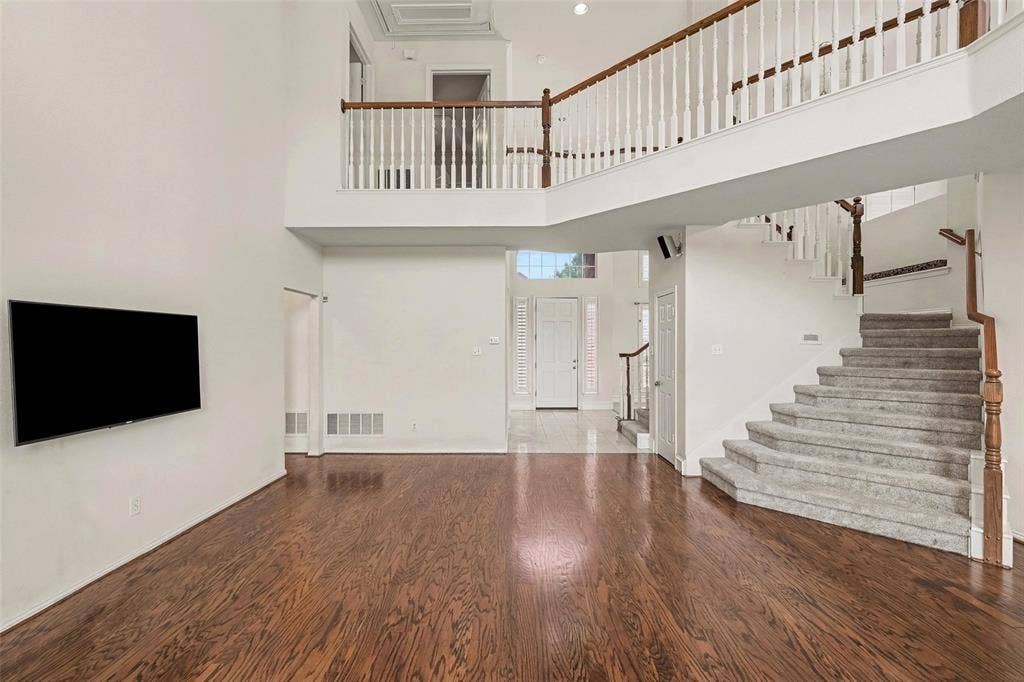 7813 San Isabel Drive, Plano, TX 75025 Two-story entry foyer with wood-finish flooring, a grand staircase with carpeted treads, and a second-story interior balcony with white balusters