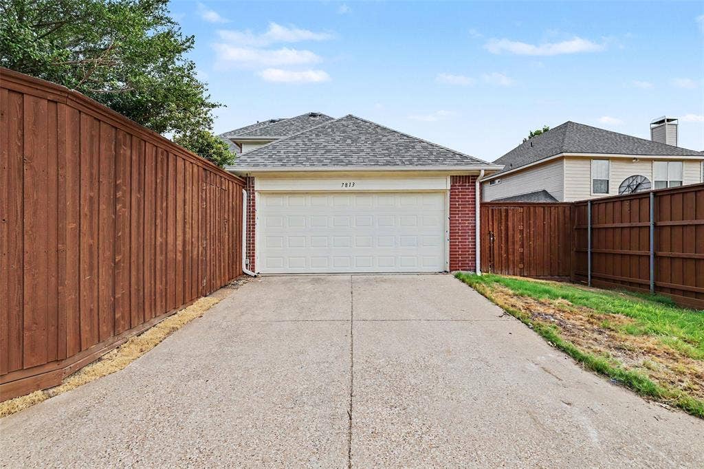7813 San Isabel Drive, Plano, TX 75025 Spacious driveway with concrete surface leading to an attached two-car garage featuring a white sectional door