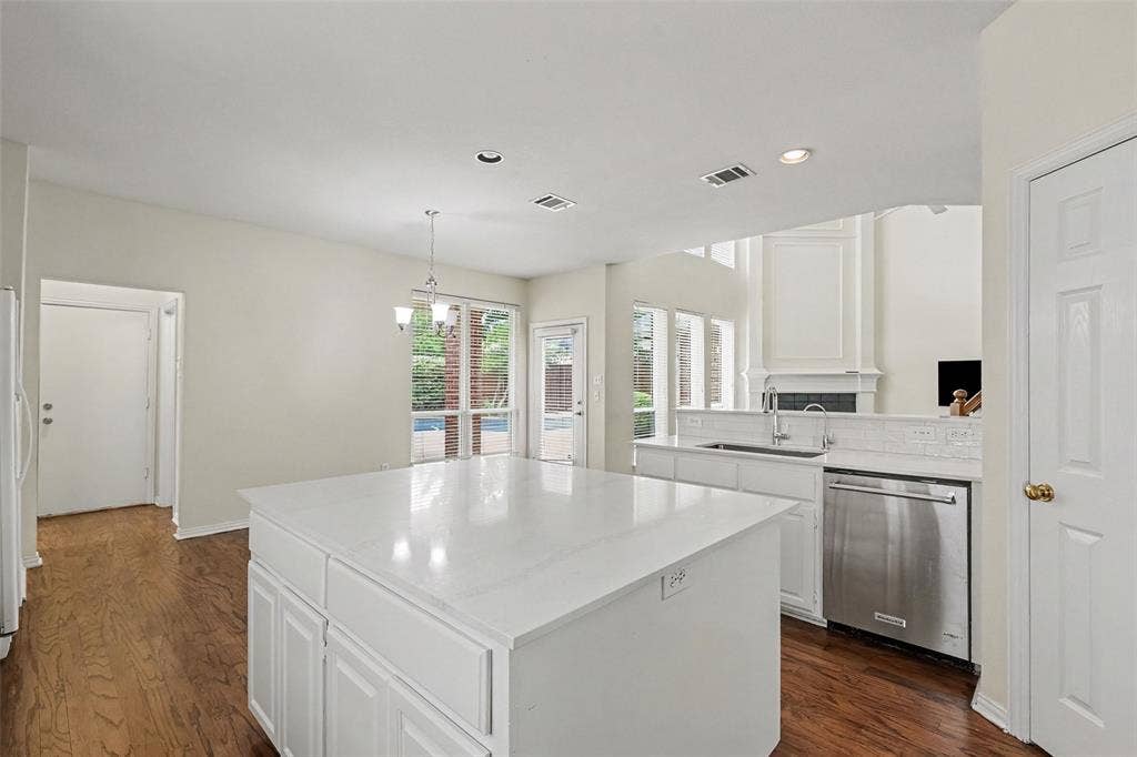 7813 San Isabel Drive, Plano, TX 75025 Kitchen island with white cabinetry and a light-toned countertop, stainless steel dishwasher, wood-finish flooring, and recessed lighting