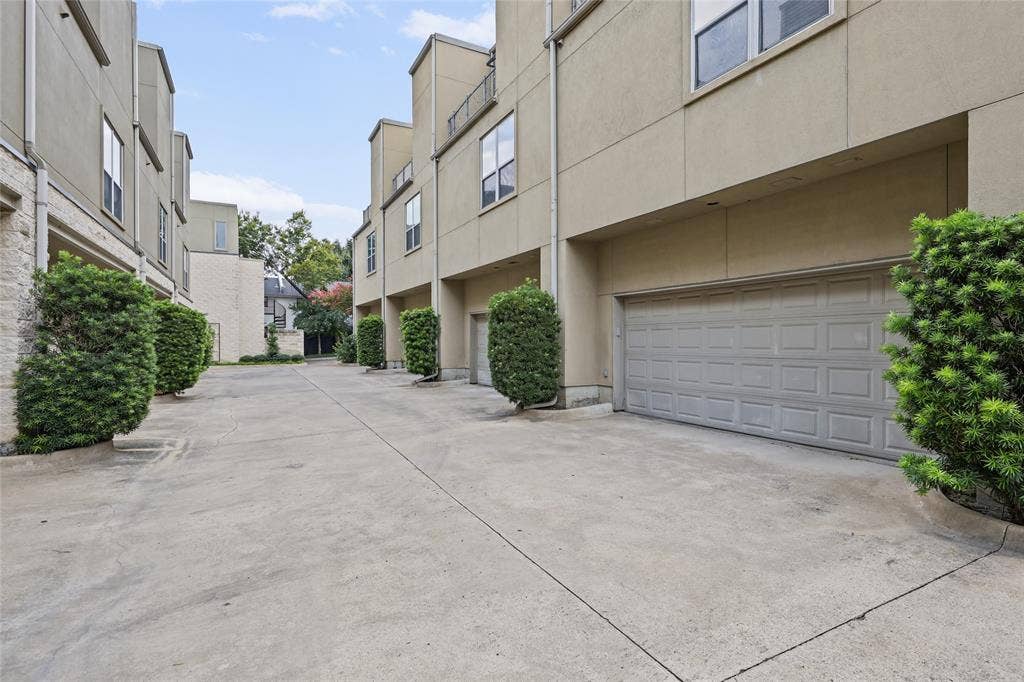 4312 Mckinney Avenue, #4, Dallas, TX 75205 Gated courtyard featuring smooth concrete hardscaping, dual garage doors with modern gray finish, and mature landscaping with sculpted hedges