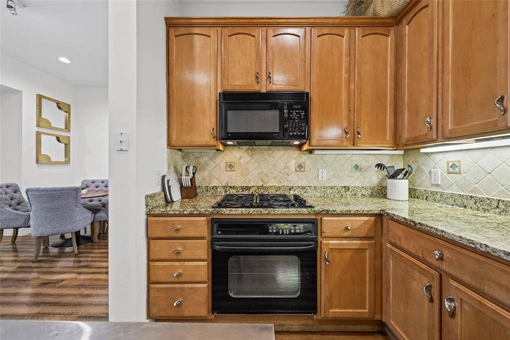 4312 Mckinney Avenue, #4, Dallas, TX 75205 Warm wood cabinetry with ample storage and brushed nickel hardware, granite countertops, and a coordinating tile backsplash