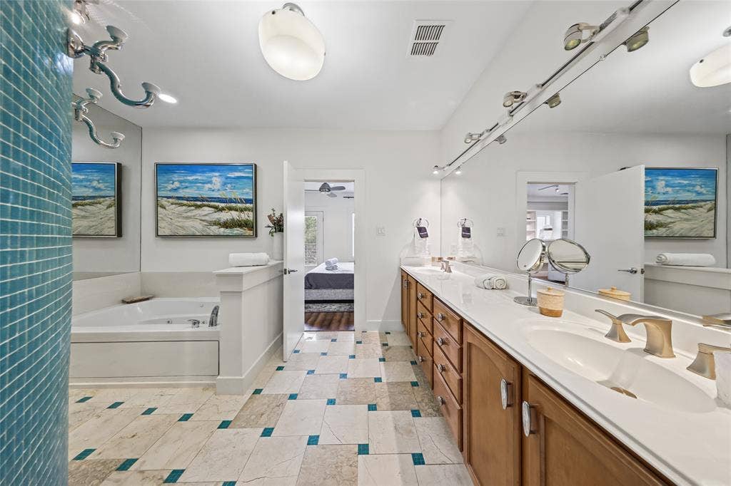 4312 Mckinney Avenue, #4, Dallas, TX 75205 Dual vanity with undermount sinks and brushed nickel fixtures, wood-finish cabinetry, track lighting, corner soaking tub, and patterned tile flooring