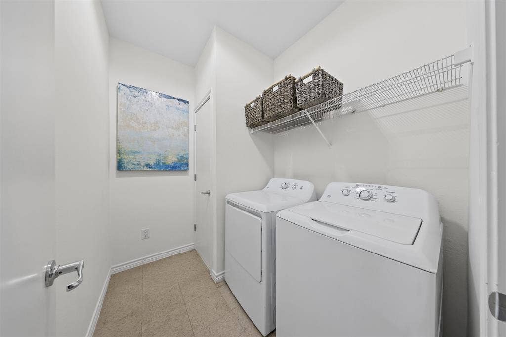 4312 Mckinney Avenue, #4, Dallas, TX 75205 Dedicated laundry room featuring side-by-side washer and dryer with white finishes, wire shelving for storage, neutral tile flooring, and soft overhead lighting