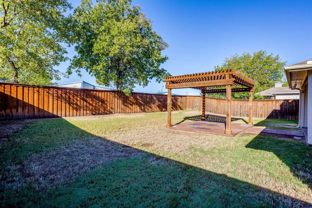 Spacious backyard featuring a wood pergola over a concrete patio and a wood privacy fence