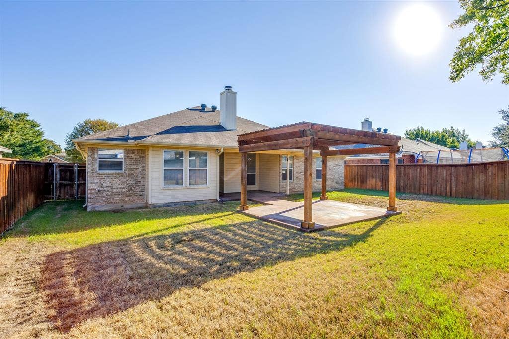 Expansive backyard featuring a wood pergola over a concrete patio and a privacy fence
