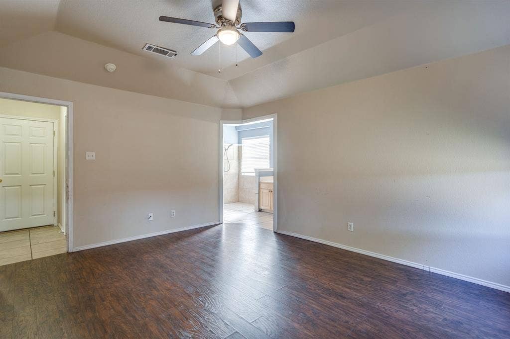 Vaulted ceiling with a ceiling fan, wood-finish flooring, and light wall tones