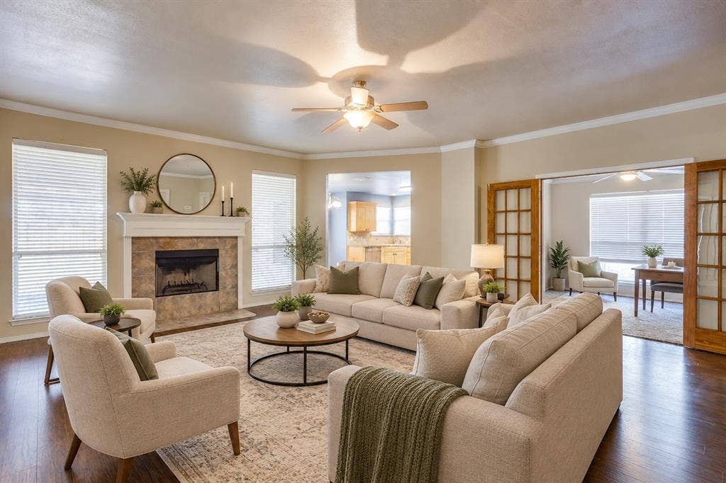 Living area featuring a stone-faced fireplace with a white mantel, wood-finish flooring, and crown molding.  virtually staged with AI