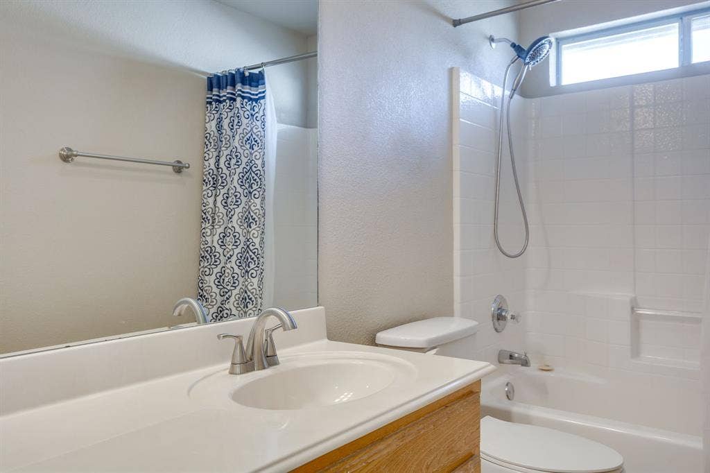 Bathroom featuring a wood-finish vanity, integrated sink, and brushed nickel faucet