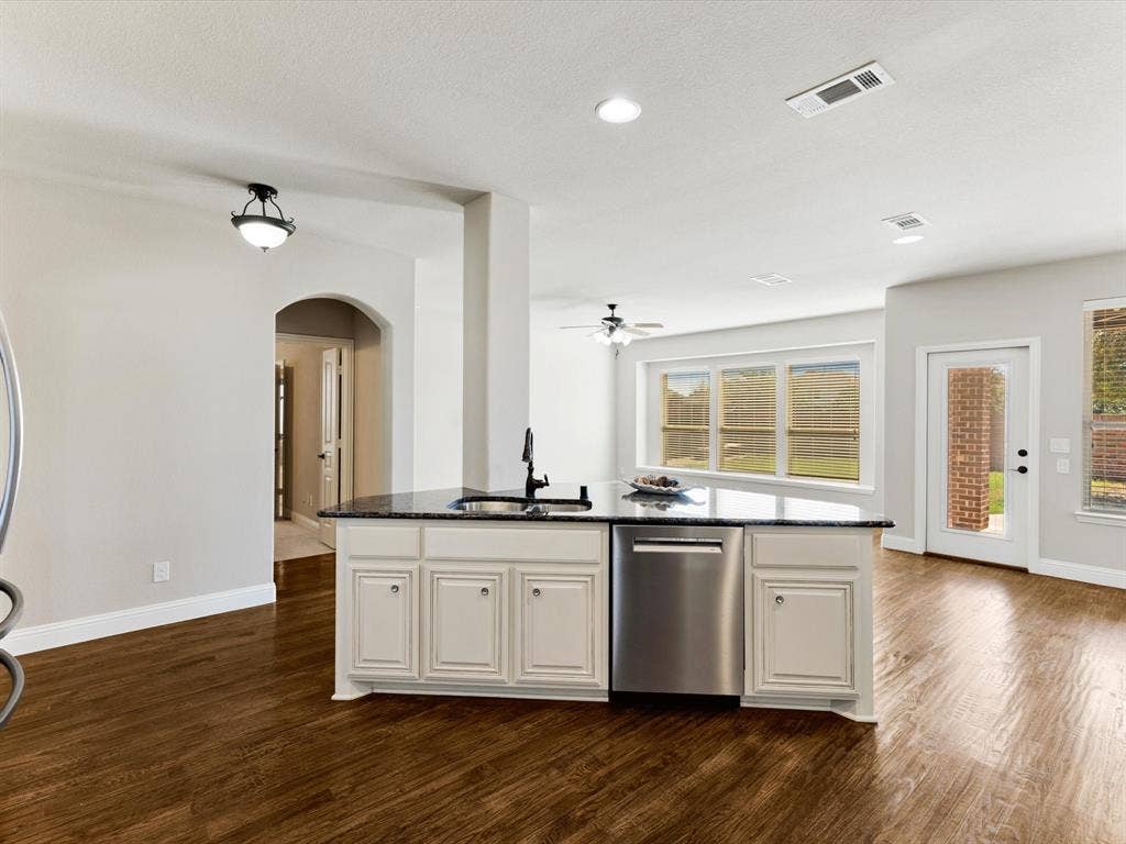 1020 Fallon Drive, McKinney, TX 75071 Kitchen island with a dark countertop, undermount sink, and stainless steel dishwasher