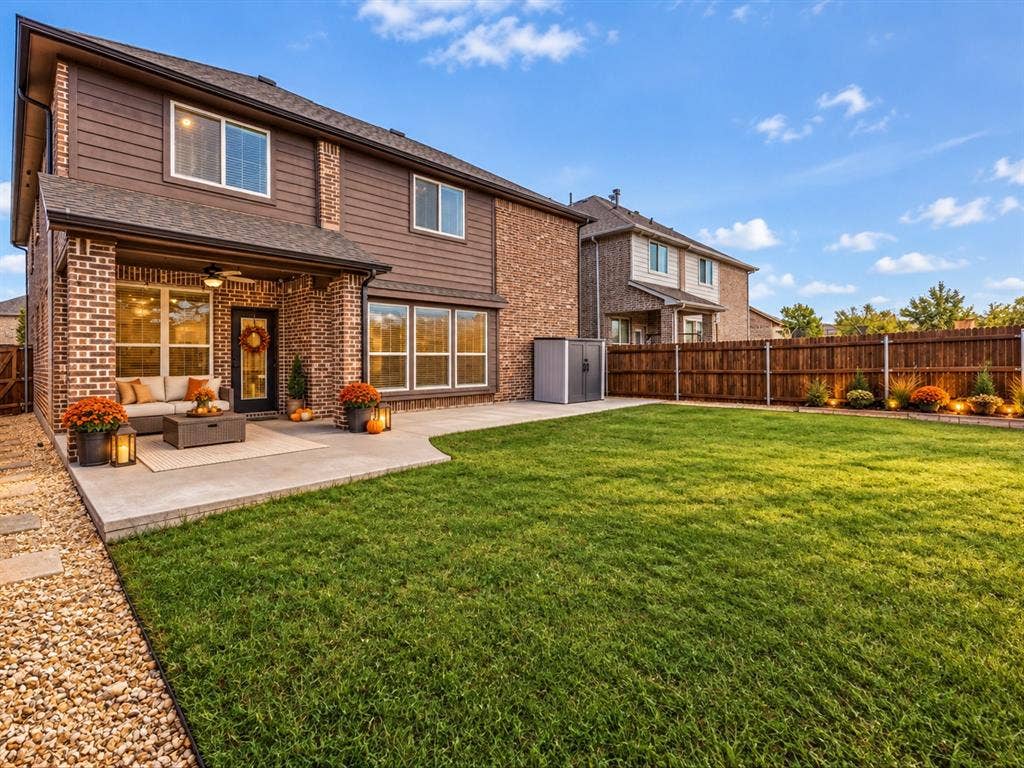 1020 Fallon Drive, McKinney, TX 75071 Expansive backyard featuring a manicured lawn, a large concrete patio, and a covered patio with an outdoor ceiling fan