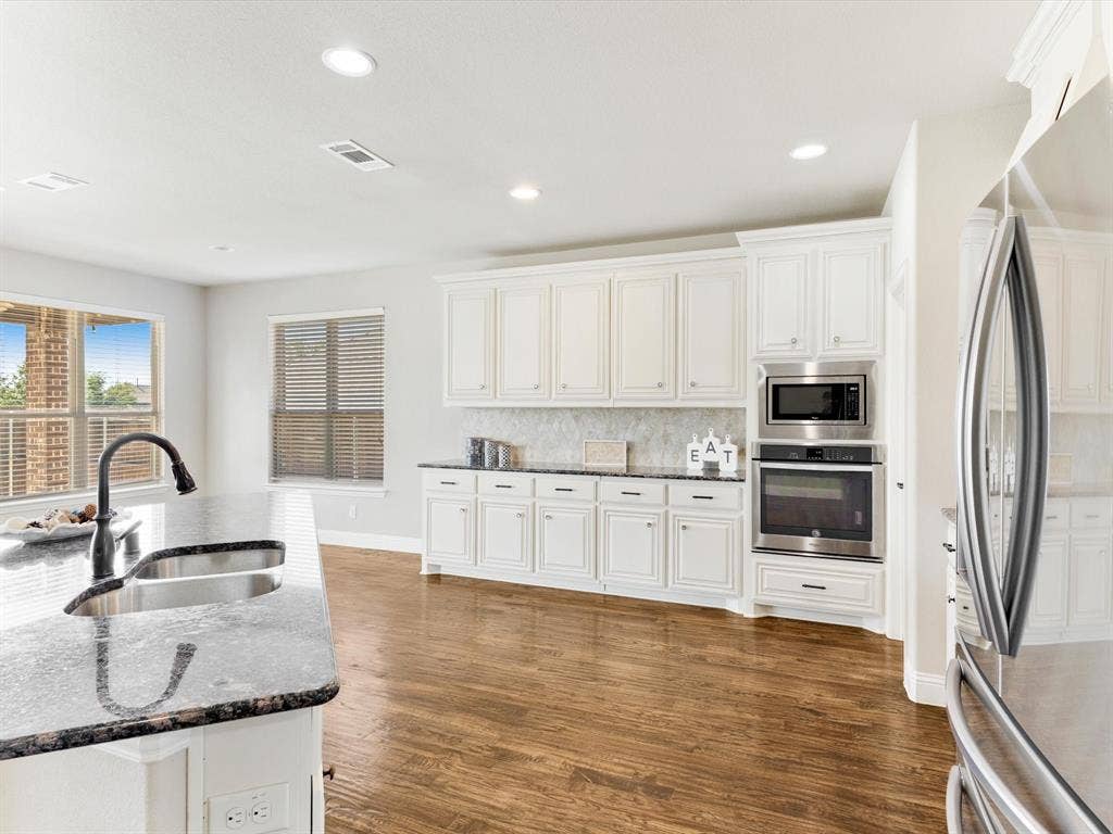 1020 Fallon Drive, McKinney, TX 75071 Kitchen featuring white cabinetry, dark stone countertops, stainless steel appliances, wood-finish flooring, and recessed lighting