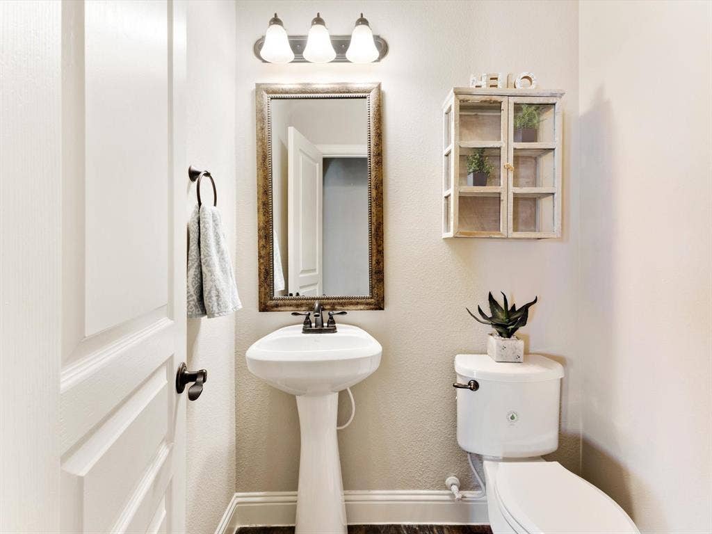 1020 Fallon Drive, McKinney, TX 75071 Pedestal sink, wall-mounted mirror with an ornate frame, and a three-light vanity fixture