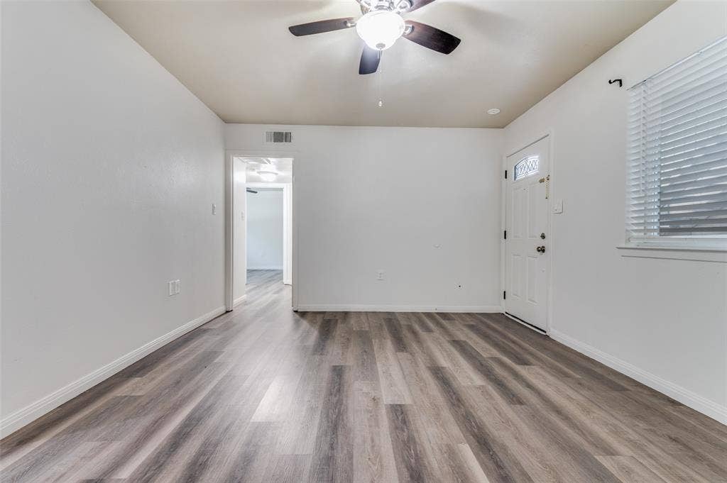 428 N Dallas Avenue, #3, Lancaster, TX 75146 Wood-finish flooring, white walls, ceiling fan with integrated lighting, window with blinds, and a paneled entry door with decorative glass inserts