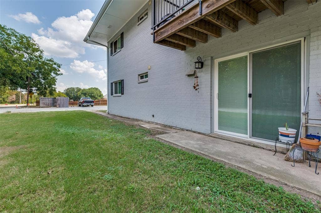 428 N Dallas Avenue, #3, Lancaster, TX 75146 Ground-level patio with sliding glass door entry, exterior wall lantern, and mature landscaping