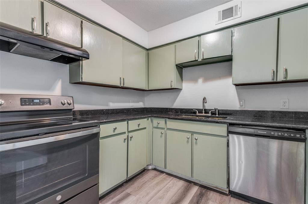 428 N Dallas Avenue, #3, Lancaster, TX 75146 Kitchen featuring light green cabinetry, dark countertops, wood-finish flooring, a stainless steel dishwasher, and a stainless steel range