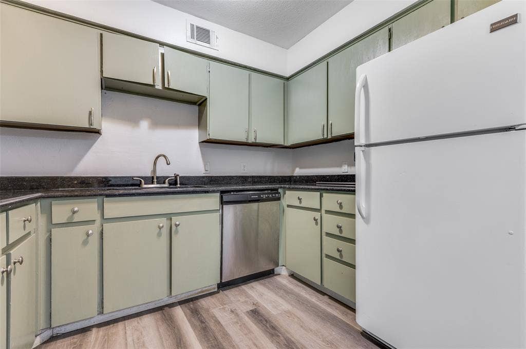 428 N Dallas Avenue, #3, Lancaster, TX 75146 Kitchen featuring wood-finish flooring, light-toned cabinetry, dark countertops, a stainless steel dishwasher, and a white refrigerator