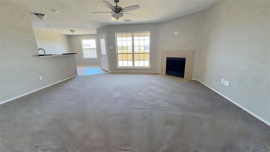 Carpeted living area featuring a built-in fireplace, ceiling fan, and multiple windows