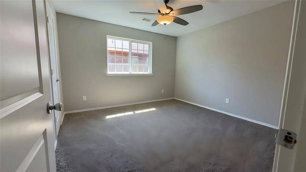Neutral-toned walls, gray carpeting, a multi-pane window, and a ceiling fan with integrated lighting