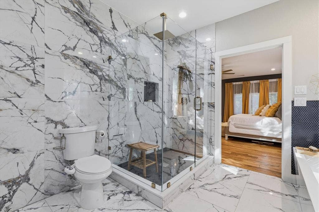 709 Woodbine Avenue, Dallas, TX 75203 Glass-enclosed shower with a built-in niche, white and gray veined tile flooring, coordinating wall tile, and recessed lighting