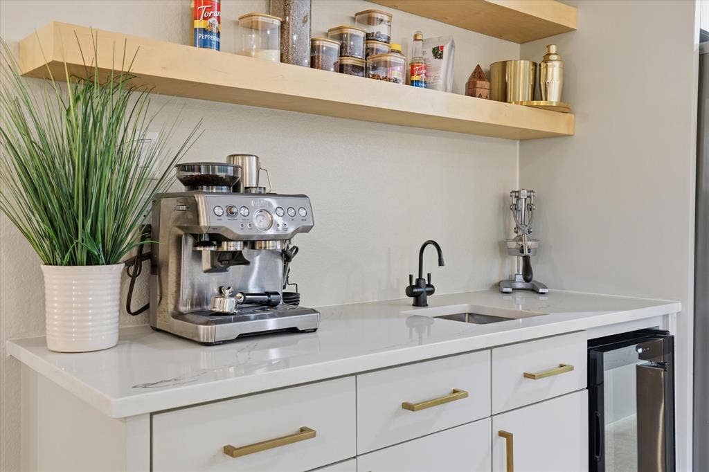 709 Woodbine Avenue, Dallas, TX 75203 White countertop with an undermount sink, a matte black faucet, and light wood-finish floating shelves