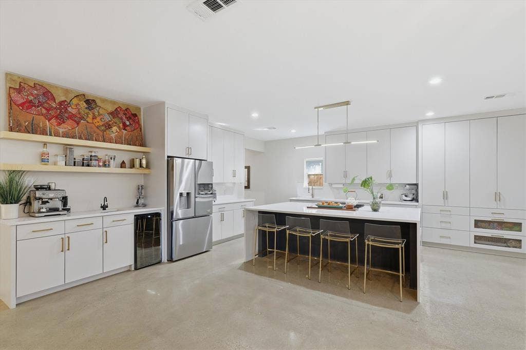 709 Woodbine Avenue, Dallas, TX 75203 Spacious kitchen featuring white cabinetry, a large kitchen island with seating, a built-in beverage refrigerator, and stainless steel appliances