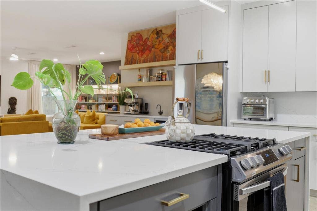 709 Woodbine Avenue, Dallas, TX 75203 Kitchen island with integrated gas range, light countertops, white upper cabinetry, gray lower cabinetry, and stainless steel appliances