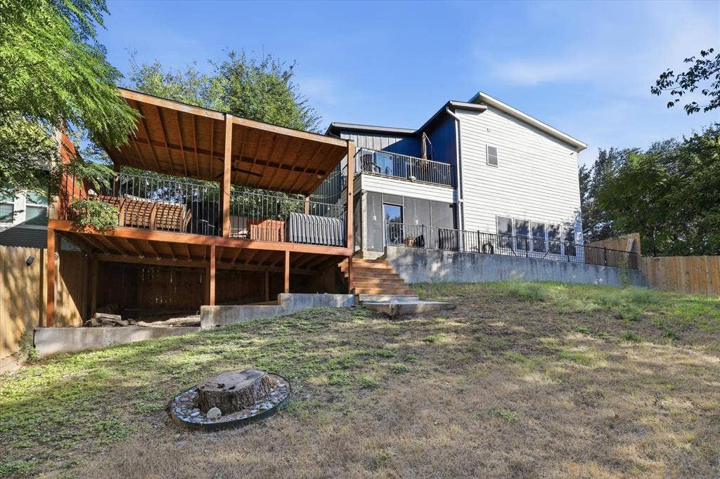 709 Woodbine Avenue, Dallas, TX 75203 Multi-level wood deck with a partial covering, second-story balcony with metal railings, wood privacy fence, and concrete retaining walls