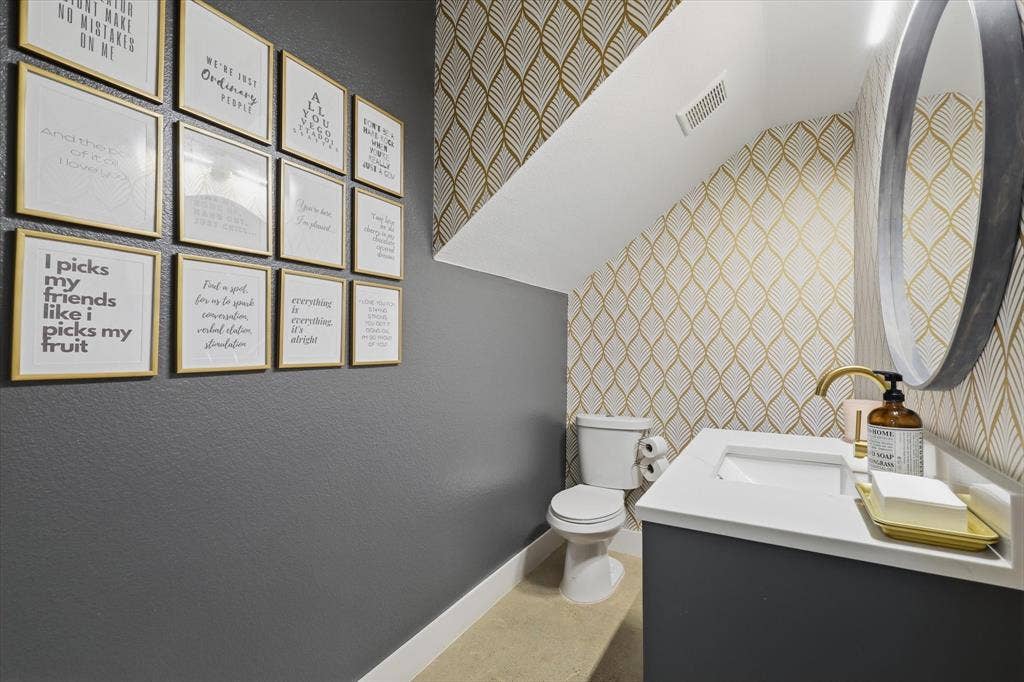 709 Woodbine Avenue, Dallas, TX 75203 Powder room featuring a single vanity with an integrated sink, a gold-finish faucet, and a round wall-mounted mirror