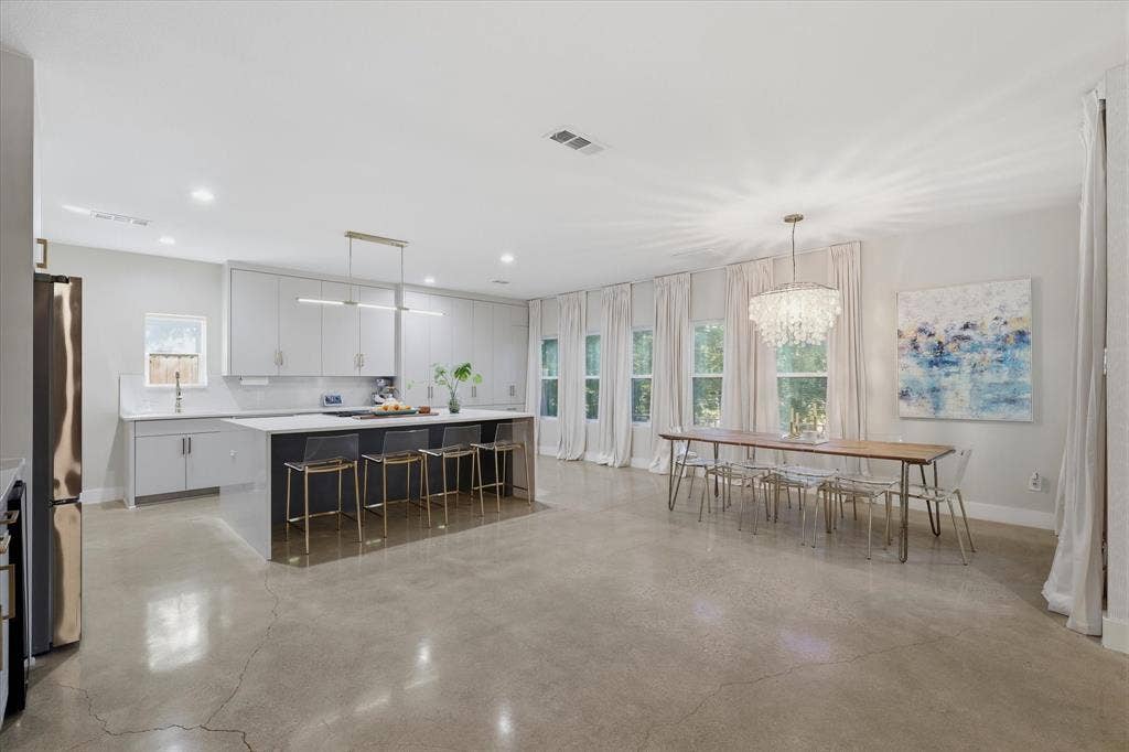 709 Woodbine Avenue, Dallas, TX 75203 Polished concrete flooring, recessed lighting, white cabinetry, kitchen island with seating, and multiple windows