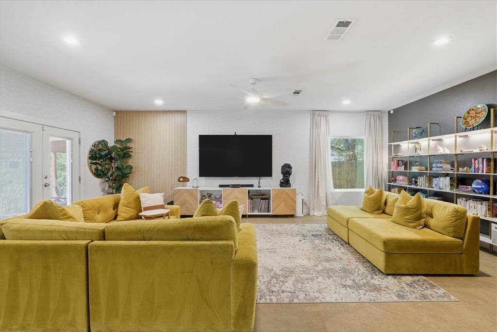 709 Woodbine Avenue, Dallas, TX 75203 Vaulted ceiling with recessed lighting, exposed concrete flooring, built-in shelving, white double-pane glass doors, and a ceiling fan