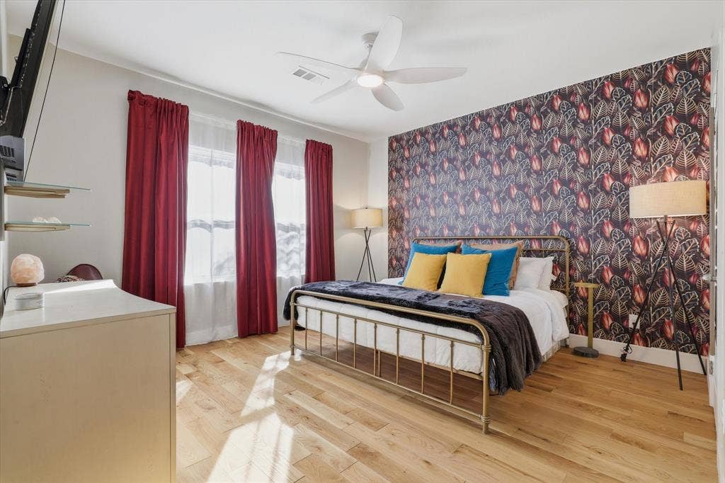 709 Woodbine Avenue, Dallas, TX 75203 Light wood flooring, accent wall with patterned wallpaper, ceiling fan, and multiple windows