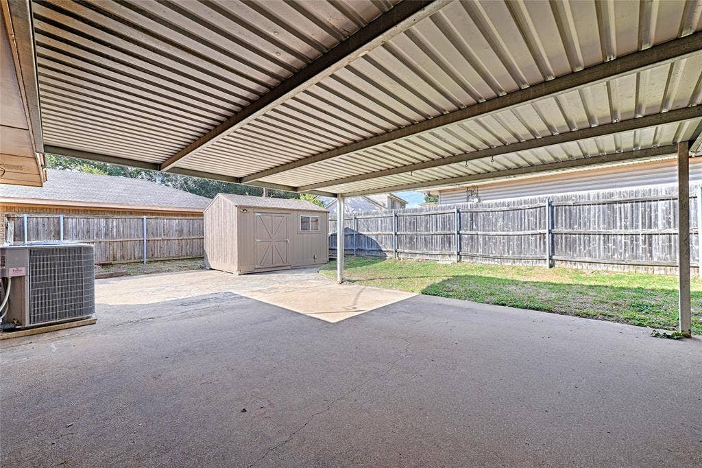 2909 Lee Park Drive, Irving, TX 75062 Covered concrete patio with a metal roof, exterior storage shed, and fenced backyard