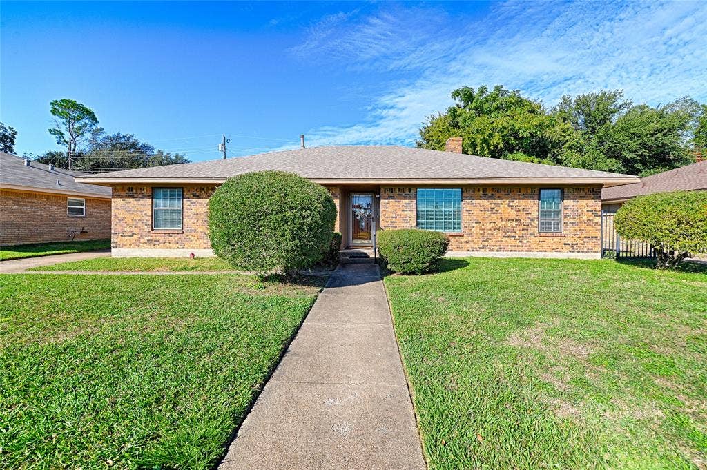 2909 Lee Park Drive, Irving, TX 75062 Single-story brick exterior featuring a hip roof, concrete walkway, and multi-pane windows