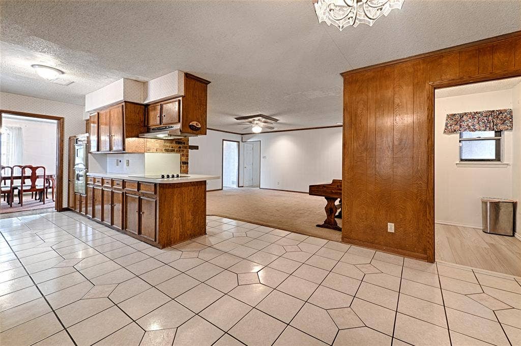 2909 Lee Park Drive, Irving, TX 75062 Kitchen featuring stained wood cabinetry, a built-in wall oven, a cooktop with a range hood, and tile flooring