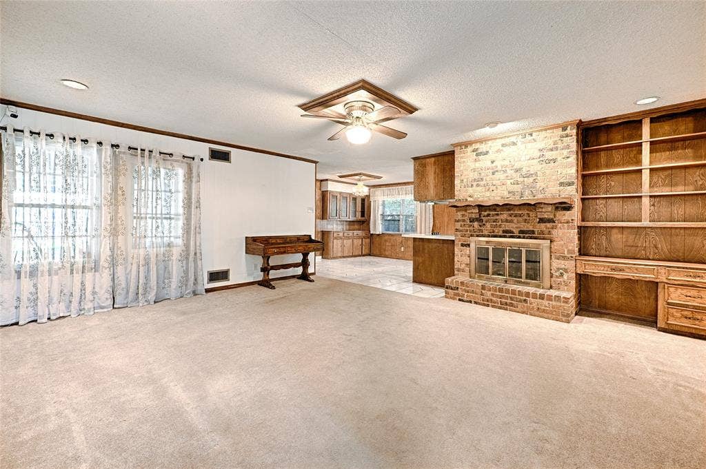 2909 Lee Park Drive, Irving, TX 75062 Living space featuring a brick fireplace with a wood mantel, built-in wooden shelving, recessed lighting, and a ceiling fan