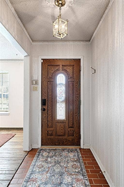 2909 Lee Park Drive, Irving, TX 75062 Entryway featuring a wood-finish front door with an integrated glass inlay, terra-cotta tile flooring, and a decorative ceiling medallion with a suspended lantern-style light fixture