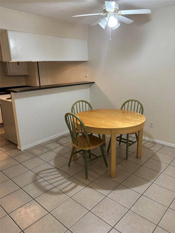 Tiled dining space featuring ceiling fan
