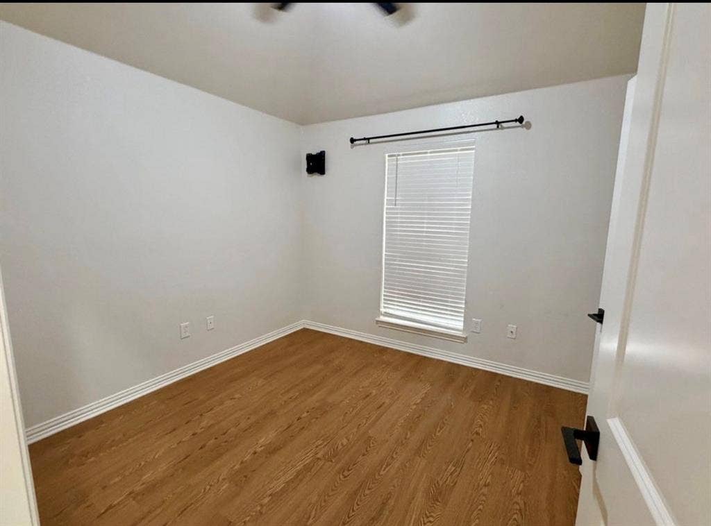 1001 Roberts Bend, Granbury, TX 76048 Wood-finish flooring, white walls, and a window with blinds