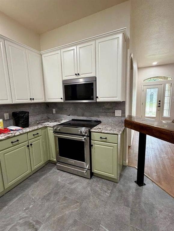 1001 Roberts Bend, Granbury, TX 76048 Kitchen featuring stainless steel range, stainless steel microwave, stone countertops, and two-tone cabinetry with black hardware