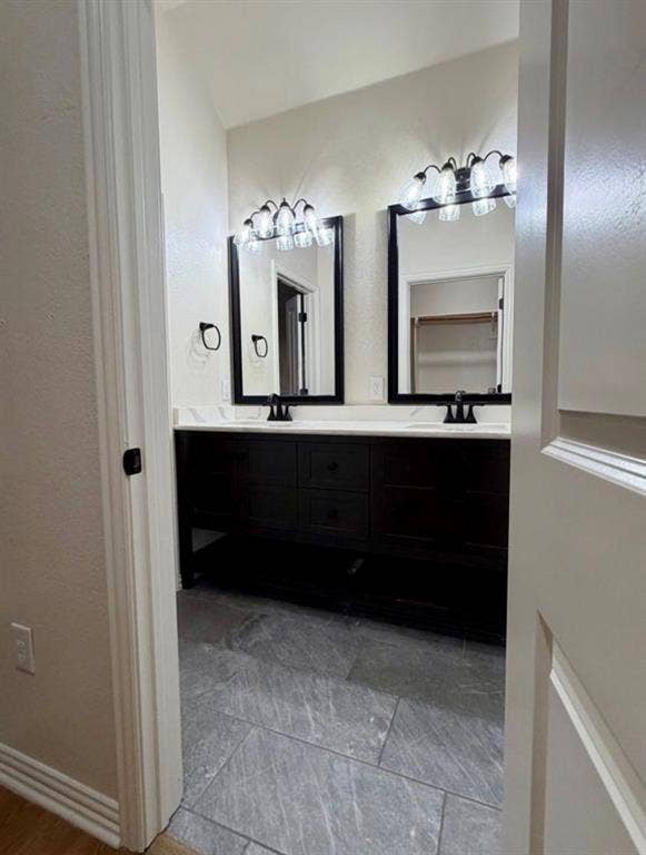 1001 Roberts Bend, Granbury, TX 76048 Double vanity with dark wood-finish cabinetry, white countertops, and dual framed mirrors