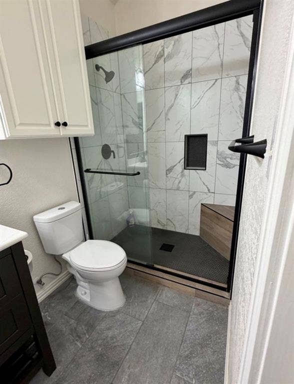 1001 Roberts Bend, Granbury, TX 76048 Modern primary bathroom featuring a frameless glass shower enclosure with matte black hardware and fixtures, marble-look tile surround, a linear floor drain, and a separate toilet with white porcelain finish