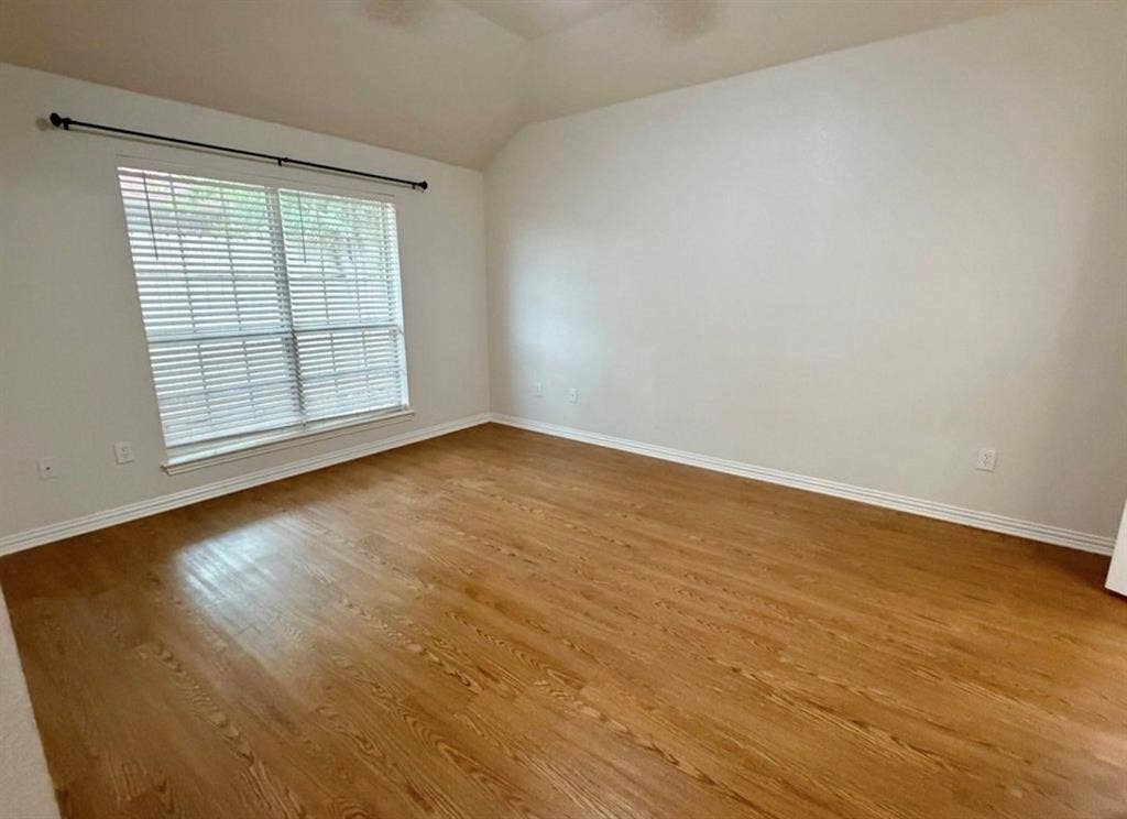 1001 Roberts Bend, Granbury, TX 76048 Vaulted ceiling, wood-finish flooring, white walls, large window with blinds, and a curtain rod