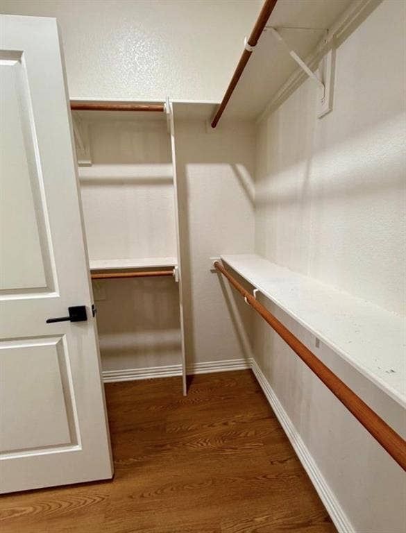 1001 Roberts Bend, Granbury, TX 76048 Walk-in closet featuring wood-finish flooring, white shelving, and hanging rods