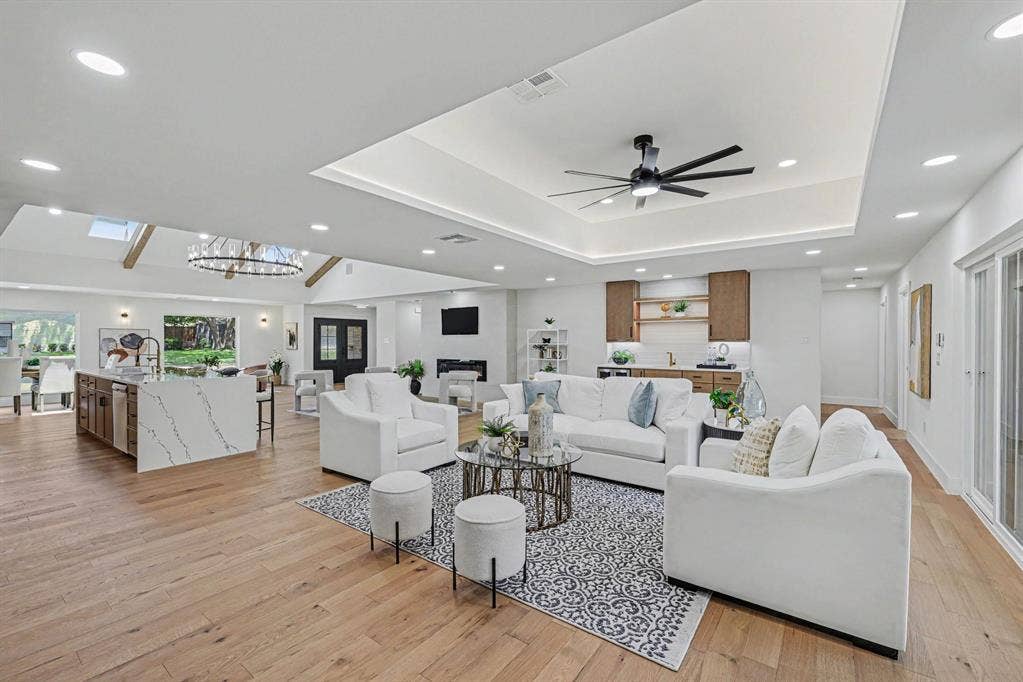 4004 Cedar Bayou Drive, Dallas, TX 75244 Wood-finish flooring throughout, tray ceiling with recessed lighting, kitchen island with waterfall countertop, built-in wet bar, and sliding glass doors