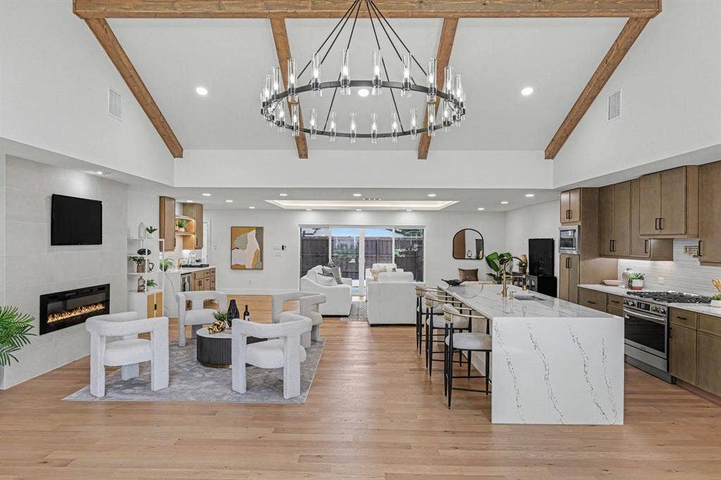4004 Cedar Bayou Drive, Dallas, TX 75244 Vaulted ceiling with exposed wood beams, wood-finish flooring, built-in electric fireplace, recessed lighting, and a kitchen island with stone countertops