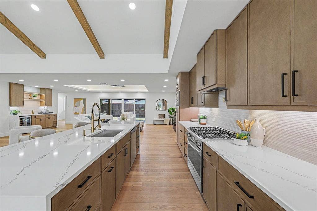4004 Cedar Bayou Drive, Dallas, TX 75244 Kitchen featuring a gas range, white quartz countertops, wood-finish flooring, and exposed ceiling beams