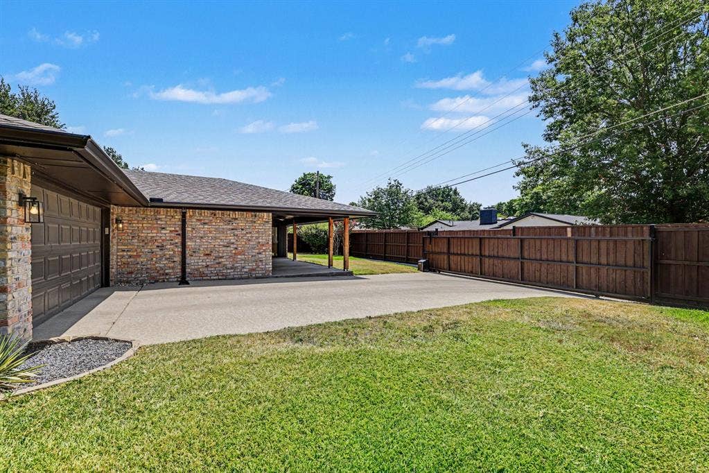 4004 Cedar Bayou Drive, Dallas, TX 75244 Brick exterior with attached garage, covered carport, concrete driveway, and wood privacy fencing
