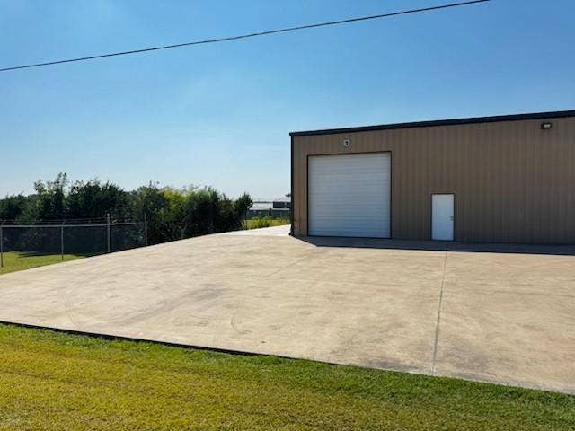 Industrial building featuring a roll-up door, personnel door, exterior lighting, and a concrete pad